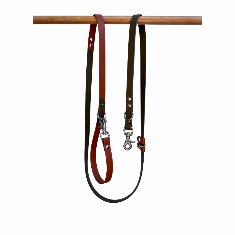 Light brown and dark brow dog leash. hanging on a wooden rod against a white background.